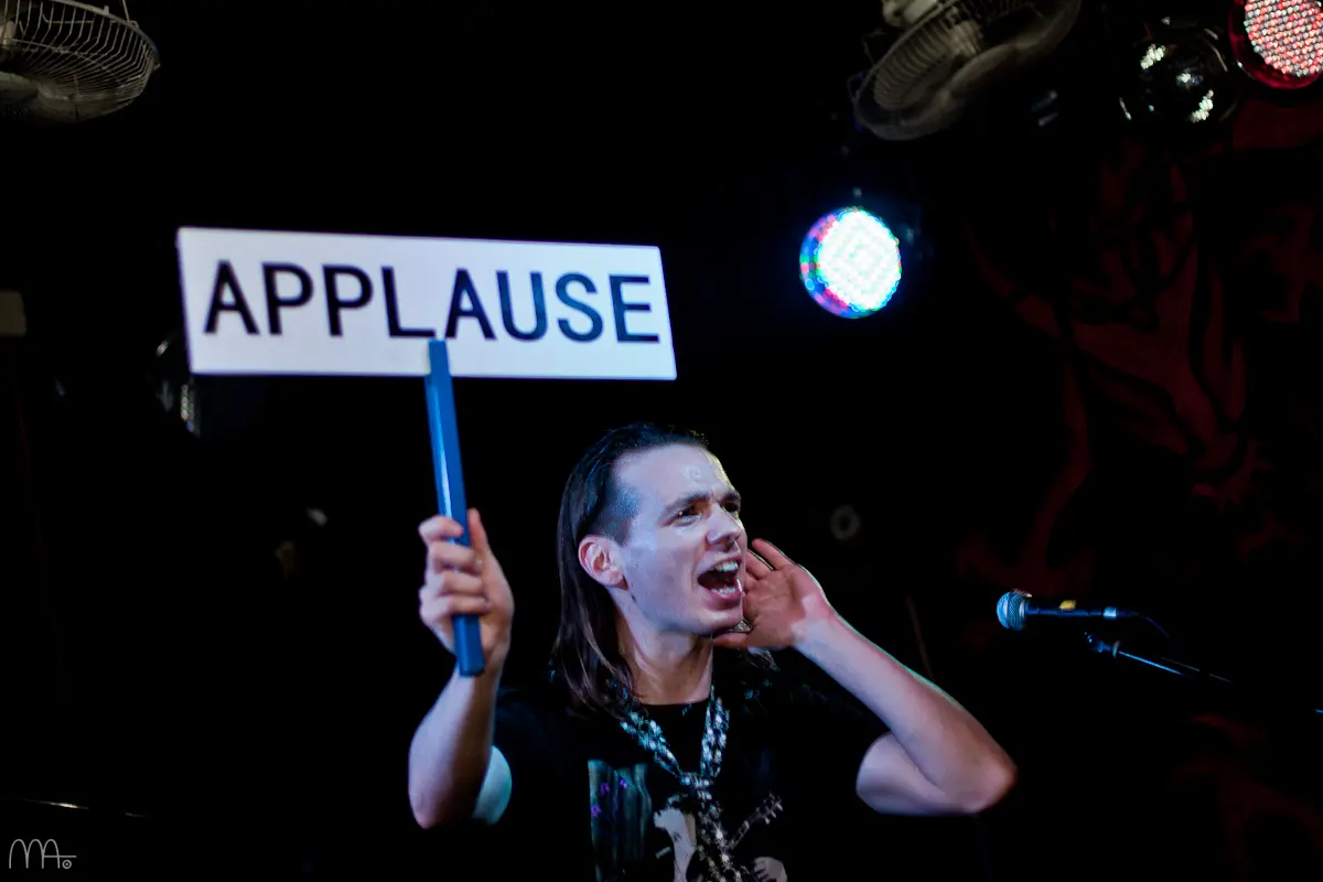 Davide holding an applause sign on stage